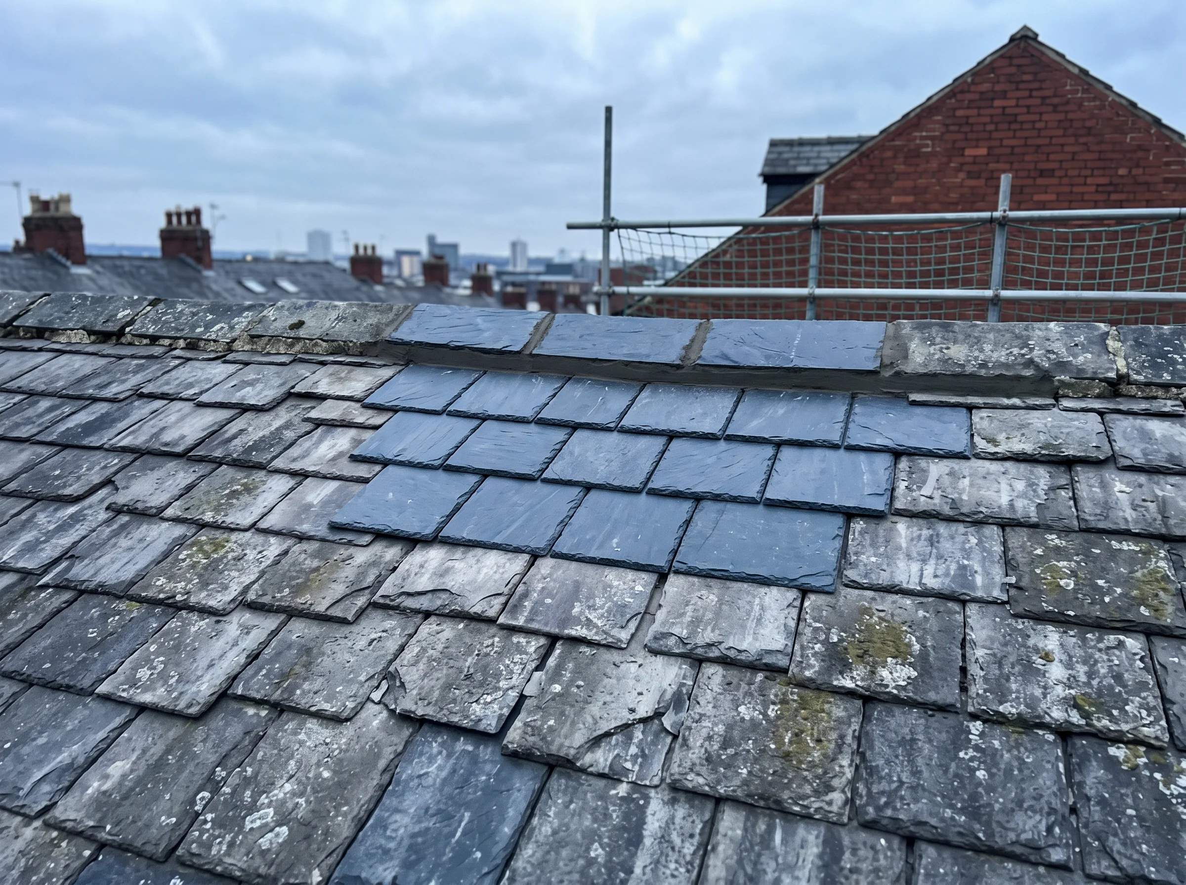 Repaired terrace roof pitch with new slates visibly darker than the weathered courses around them